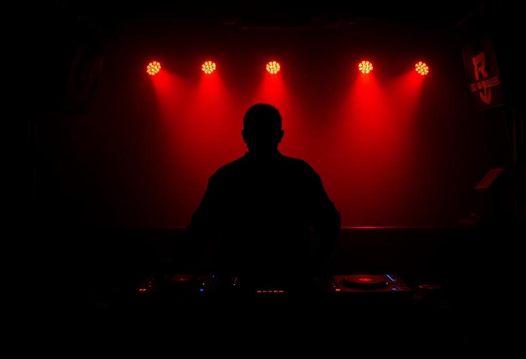 DJ silhouette behind decks in amber stage haze